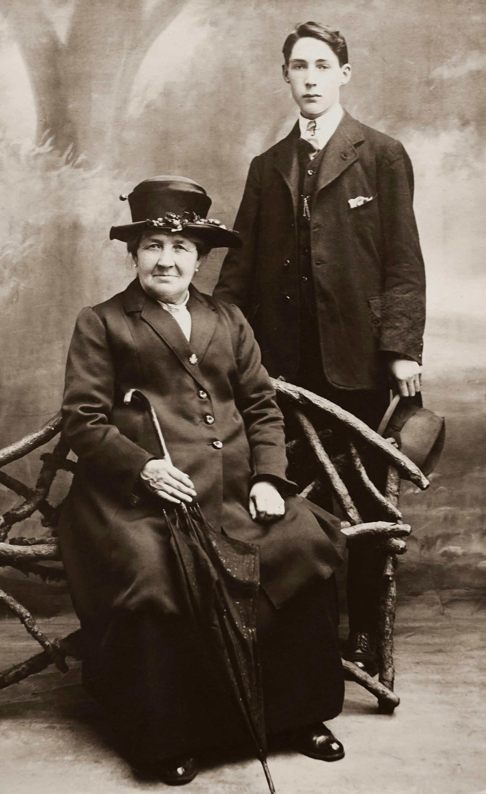 Home Classic sepia portrait featuring an elderly woman and a young man in formal attire, exuding vintage charm.