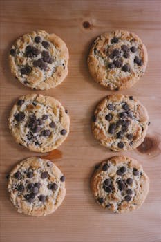 Cookies Freshly baked chocolate chip cookies arranged on a wooden surface, showcasing their tasty appeal.